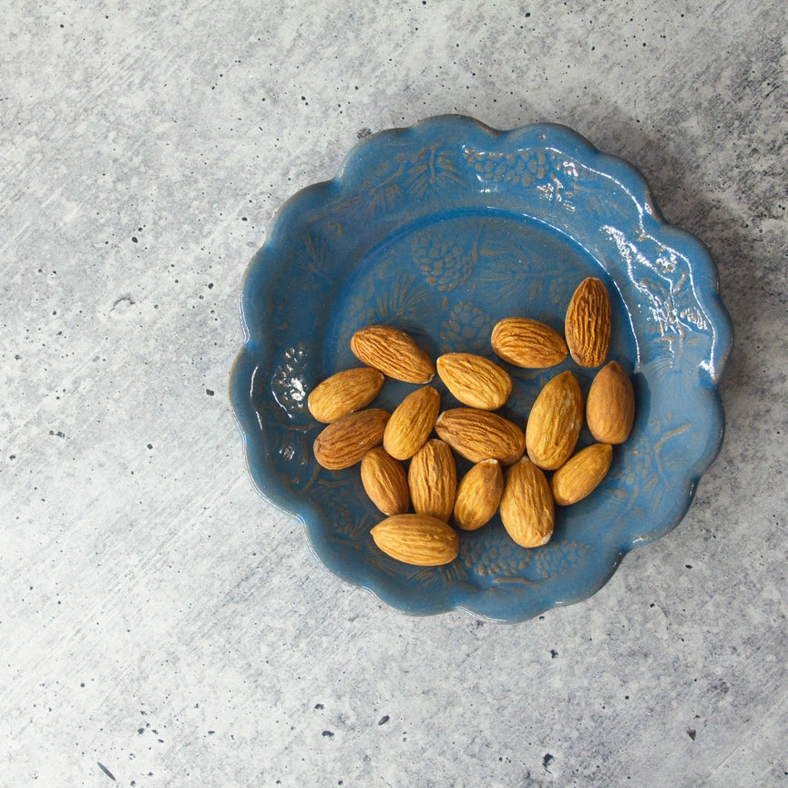 blue plate with scalloped edge and almond on grey background