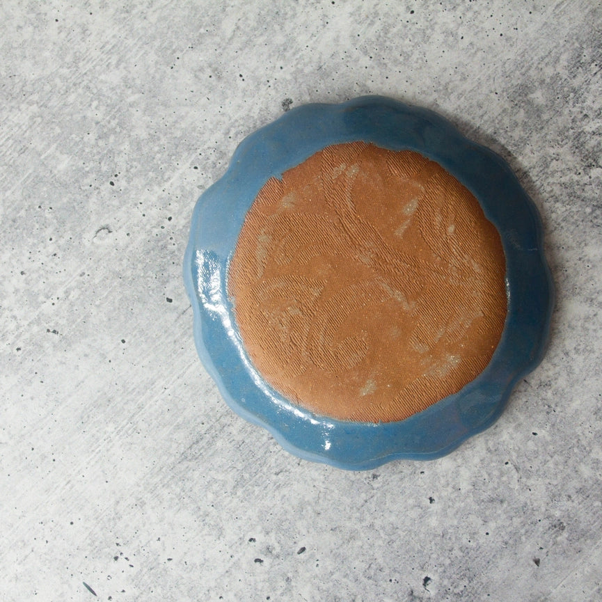 red clay round blue plate on gray background