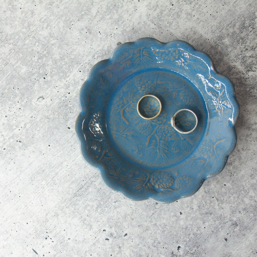 two silver rings on blue plate with scalloped edge on grey background