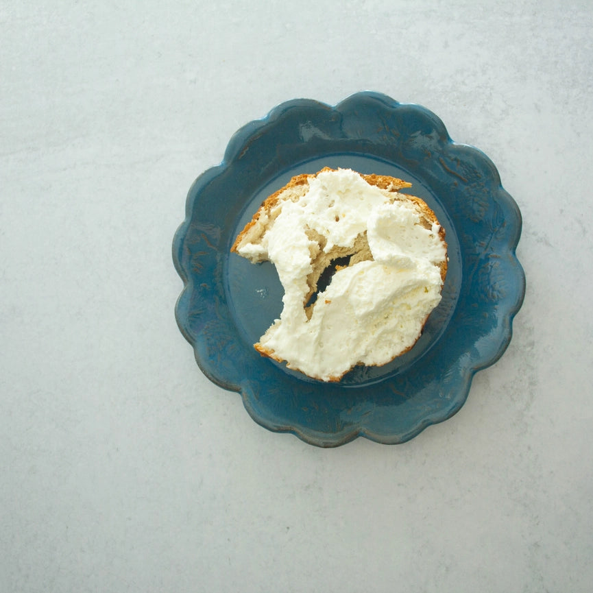 Blue plate with bagel and cream cheese on grey background