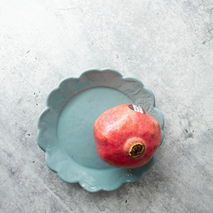 turquoise bread and butter plate scalloped edge round with fruit on gray background 