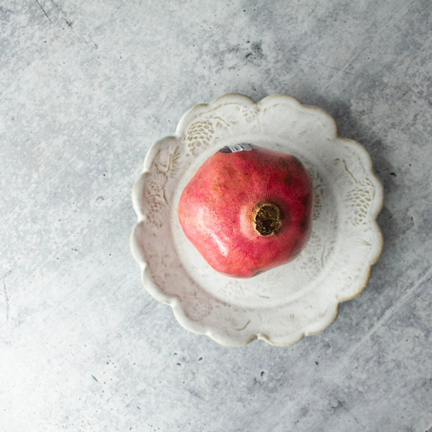 beige white ceramic plate with red fruit on grey background
