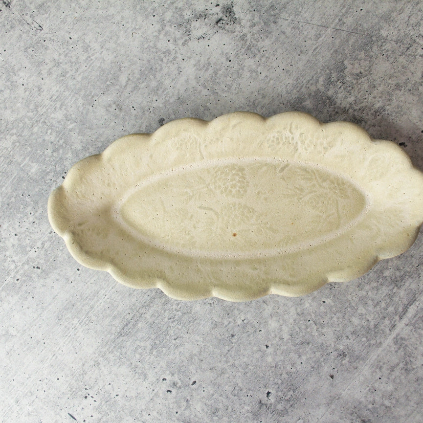 stoneware dish with scalloped edges and pin cone texture