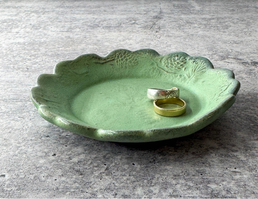 round green ceramic plate with texture, two rings and scalloped edge on grey background