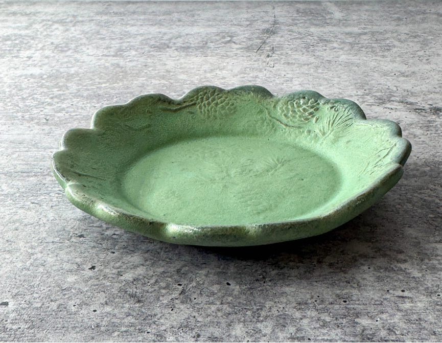 round green ceramic plate with texture and scalloped edge on grey background