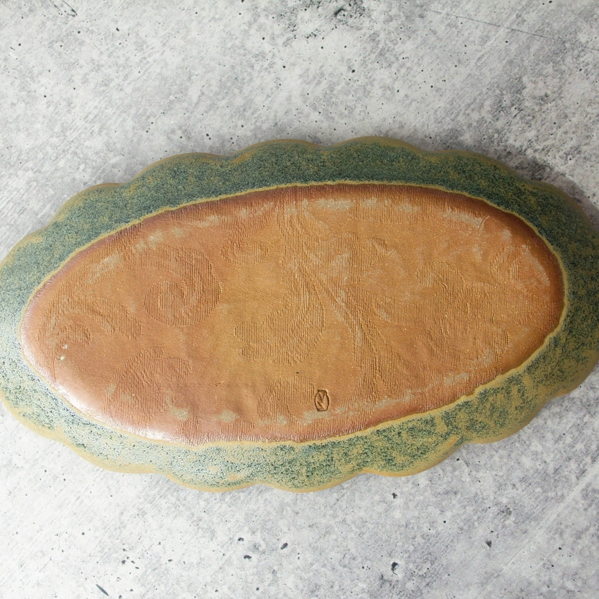 handmade green oval tray backside red clay on gray background