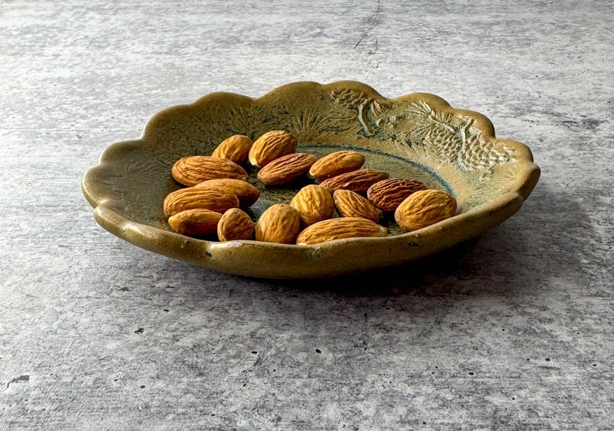yellow and green scalloped edge plate with almonds on grey background