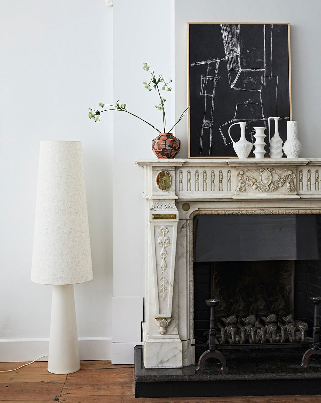 set of 4 white porcelain vases on a fire mantel in front of a black abstract painting