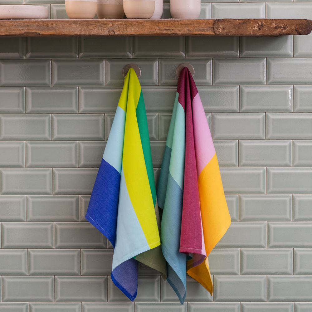 bold colored kitchen towels hanging in front of white metro tiles
