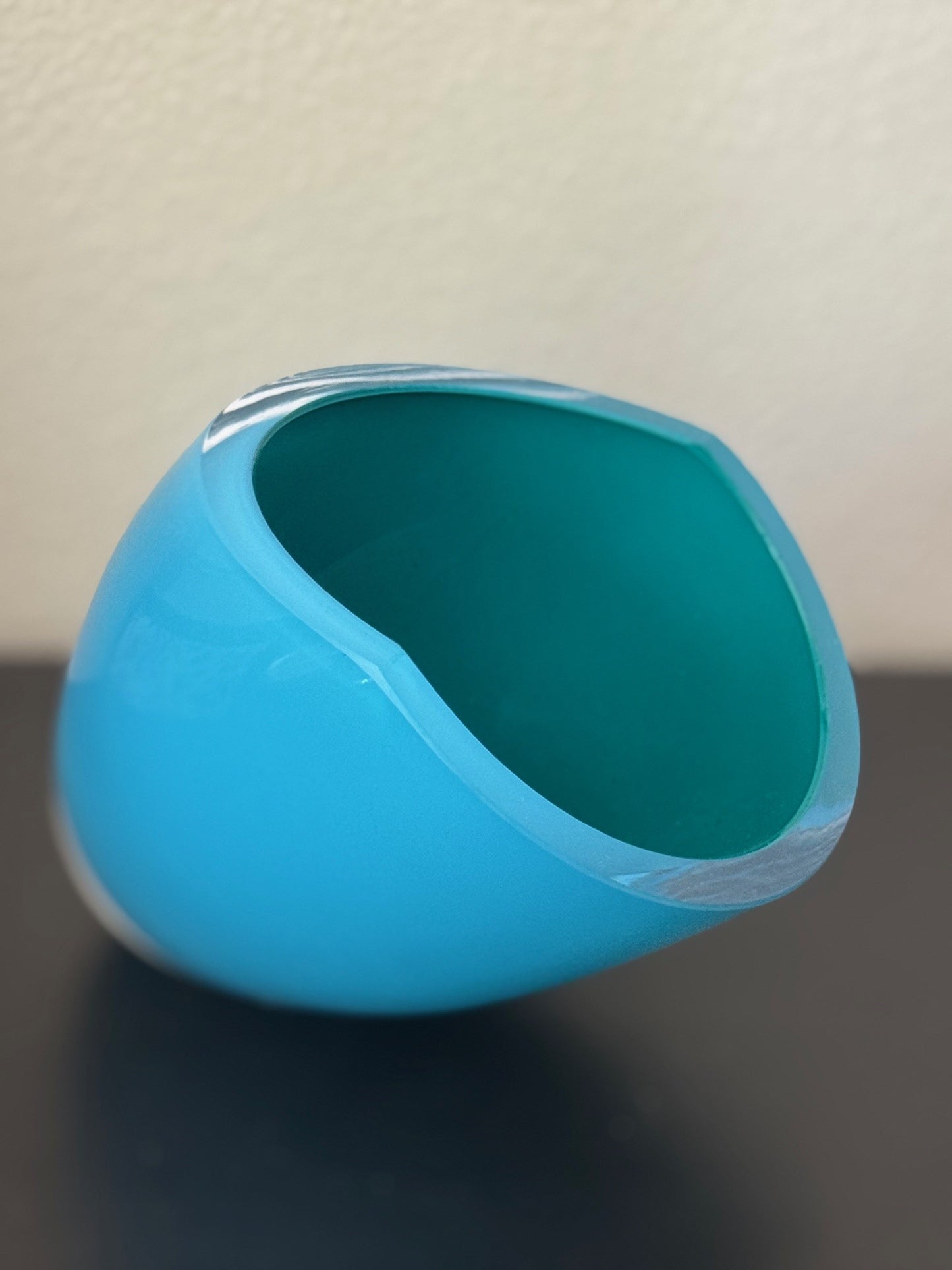 Blue glass object on a dark surface with a light background