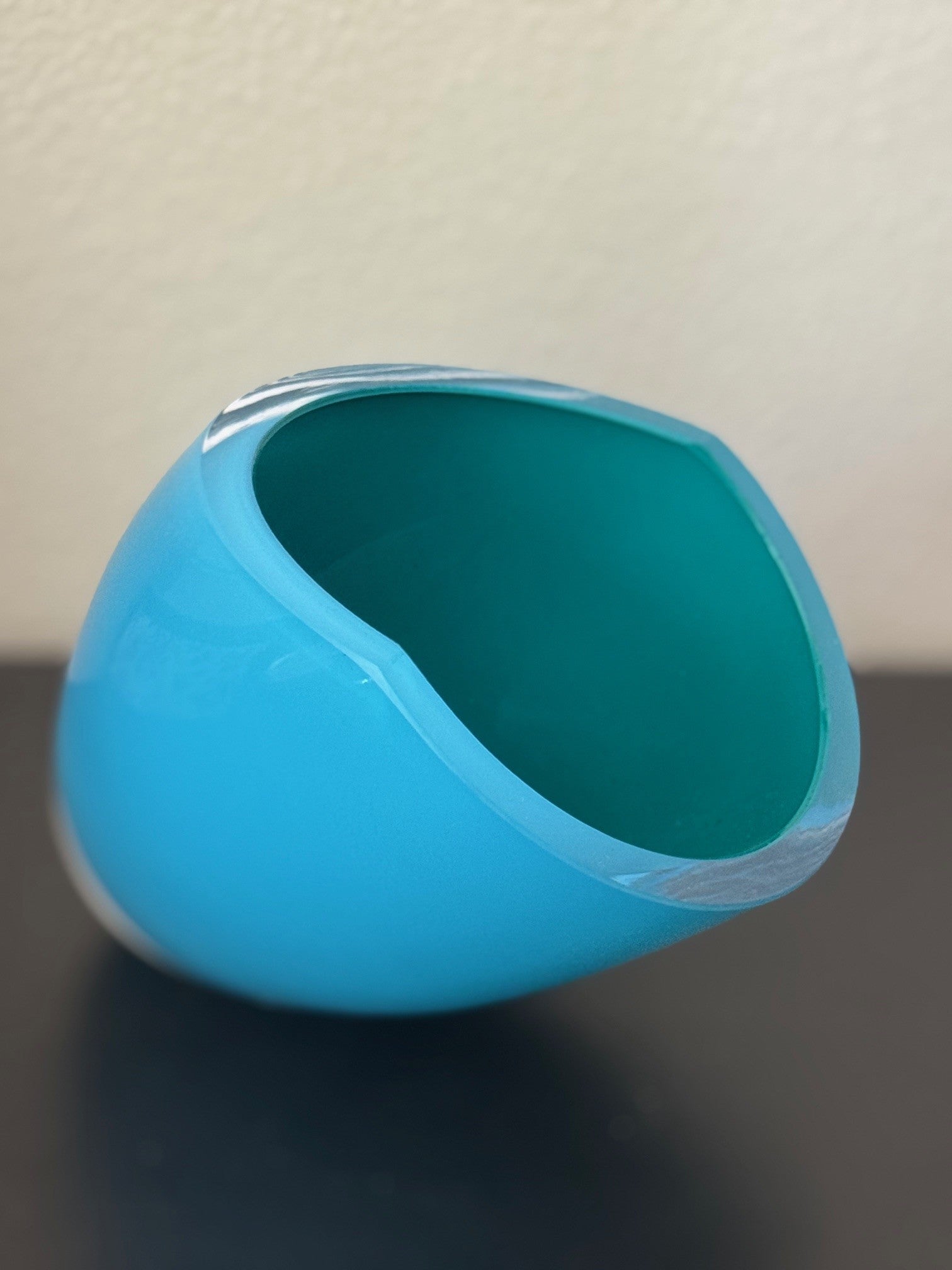 Blue glass object on a dark surface with a light background