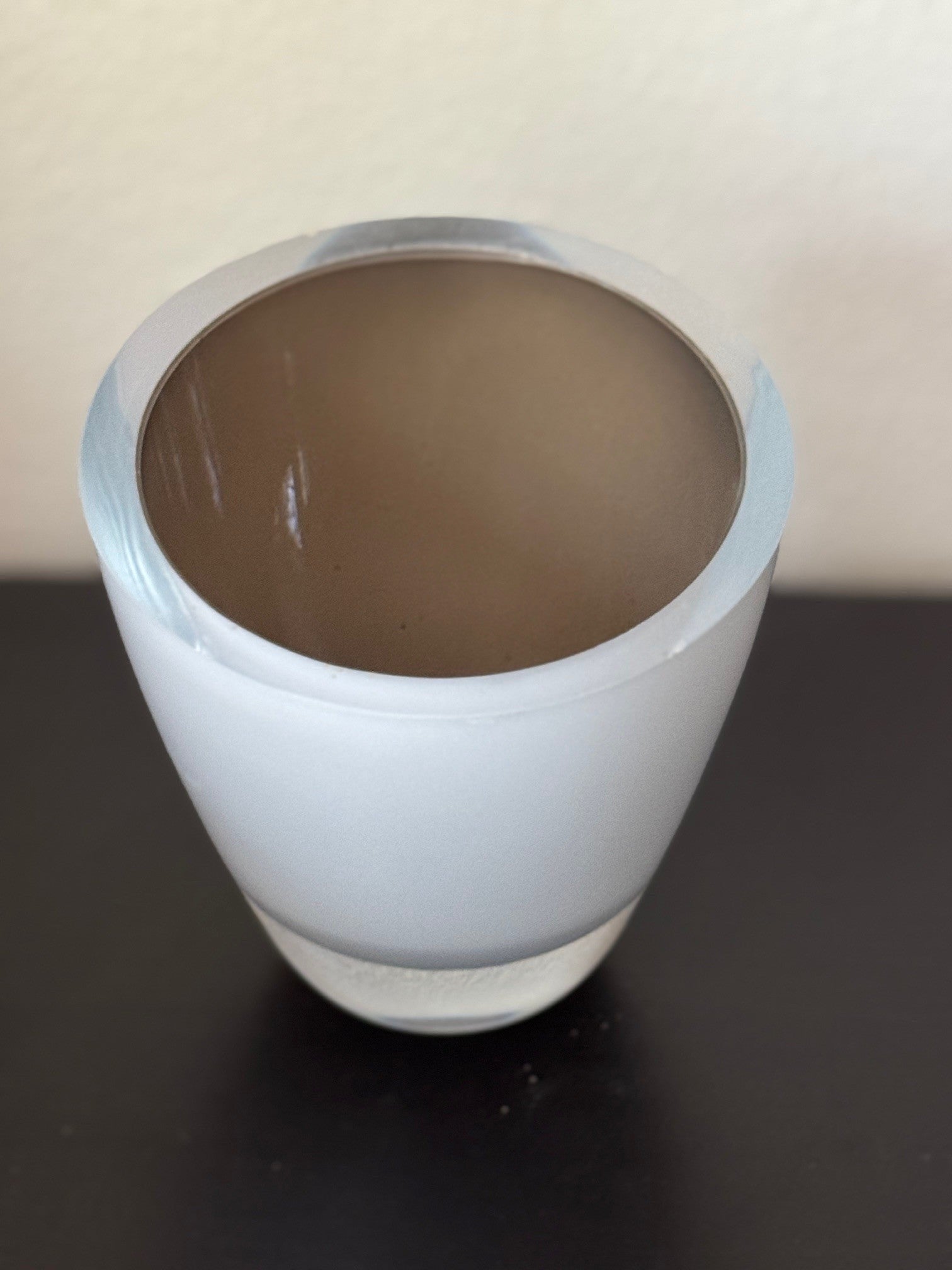 White ceramic cup with brown interior on a dark surface