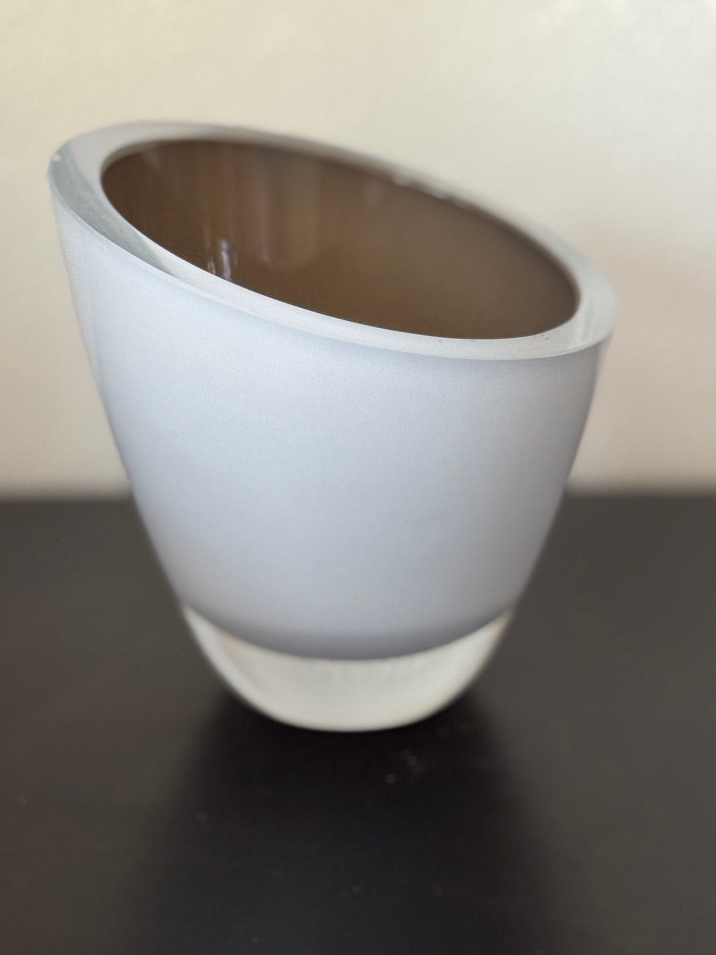 White ceramic cup on a black surface with a plain background