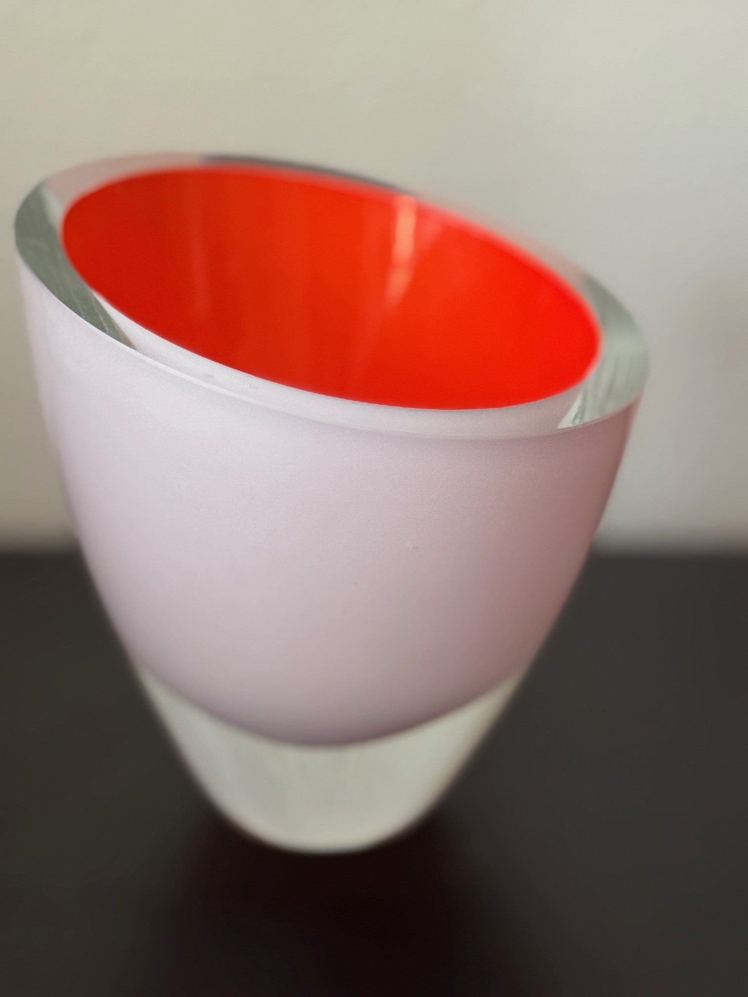 Vase with a red interior and white exterior on a dark surface