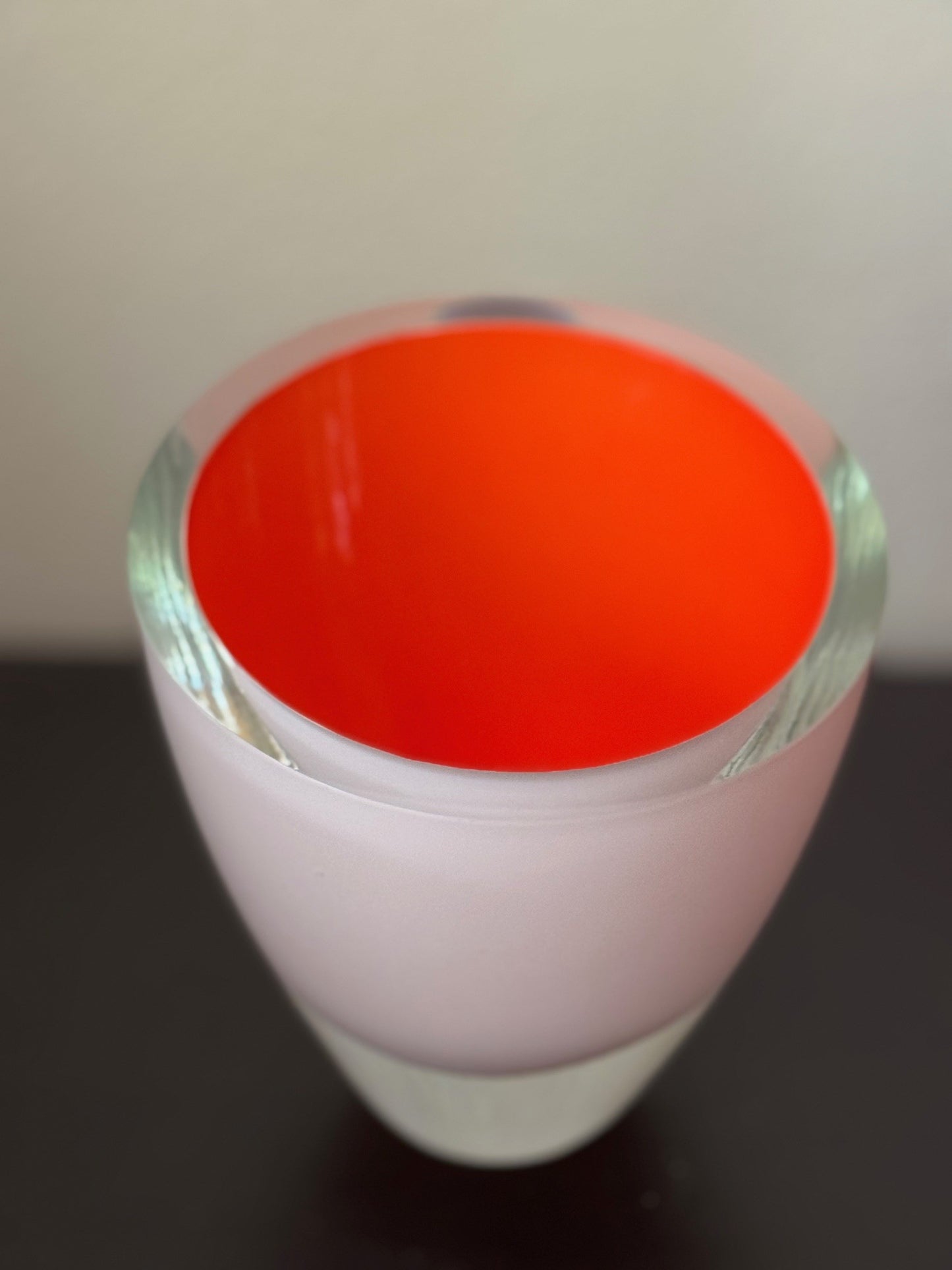 Close-up of a cylindrical object with a red top and white base on a dark surface.