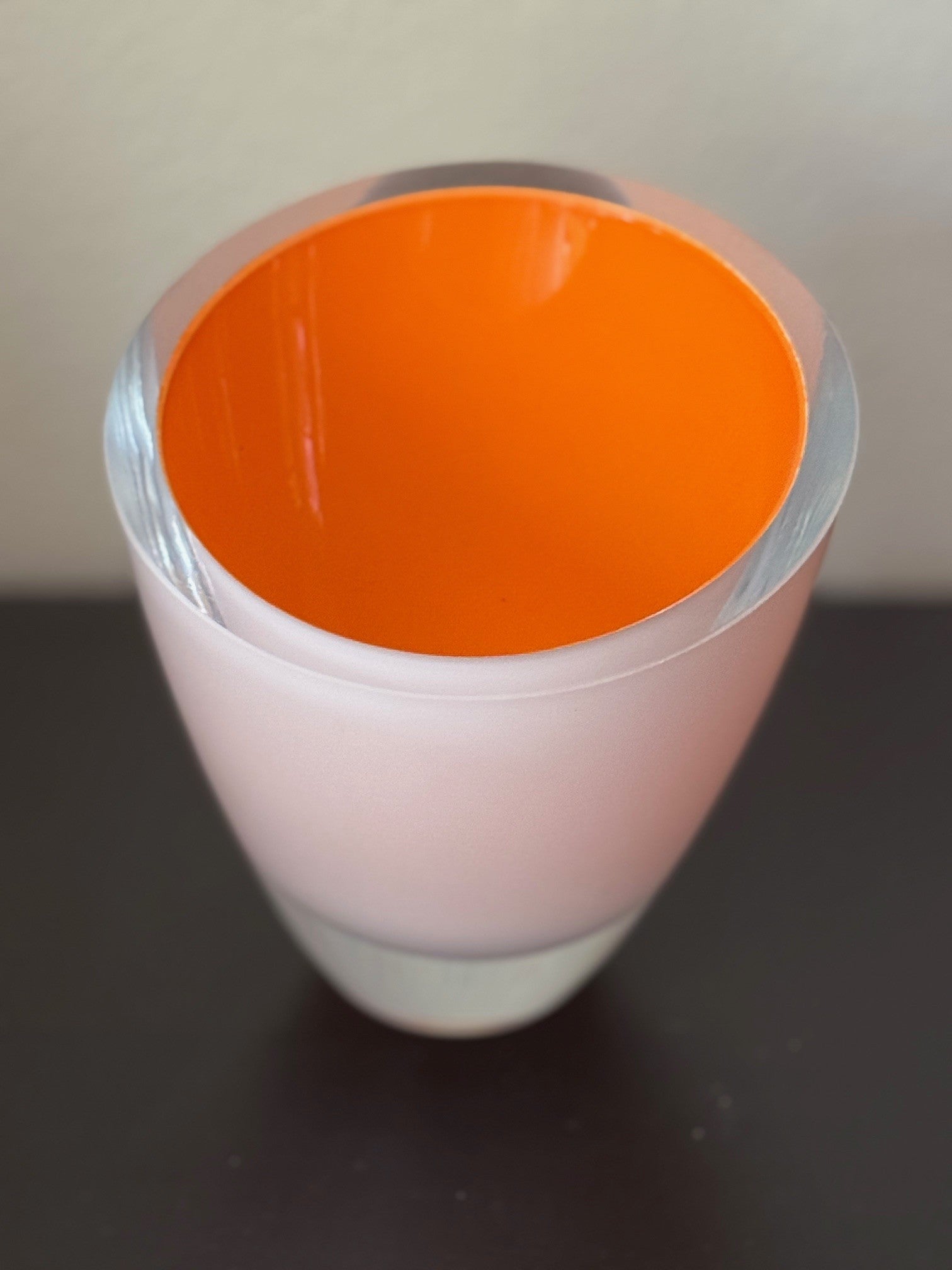 Vase with orange interior and clear exterior on a dark surface