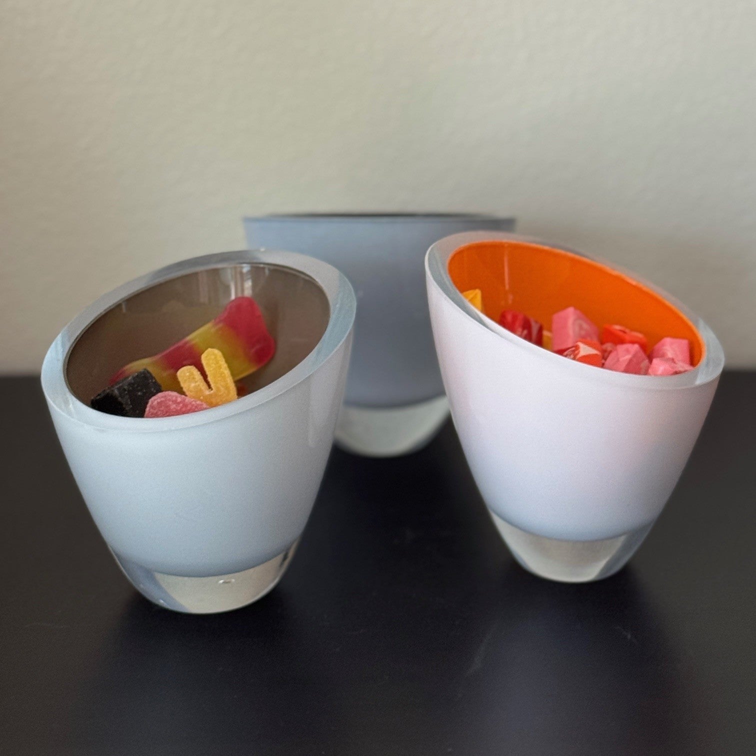 Three small bowls with colorful contents on a black surface.