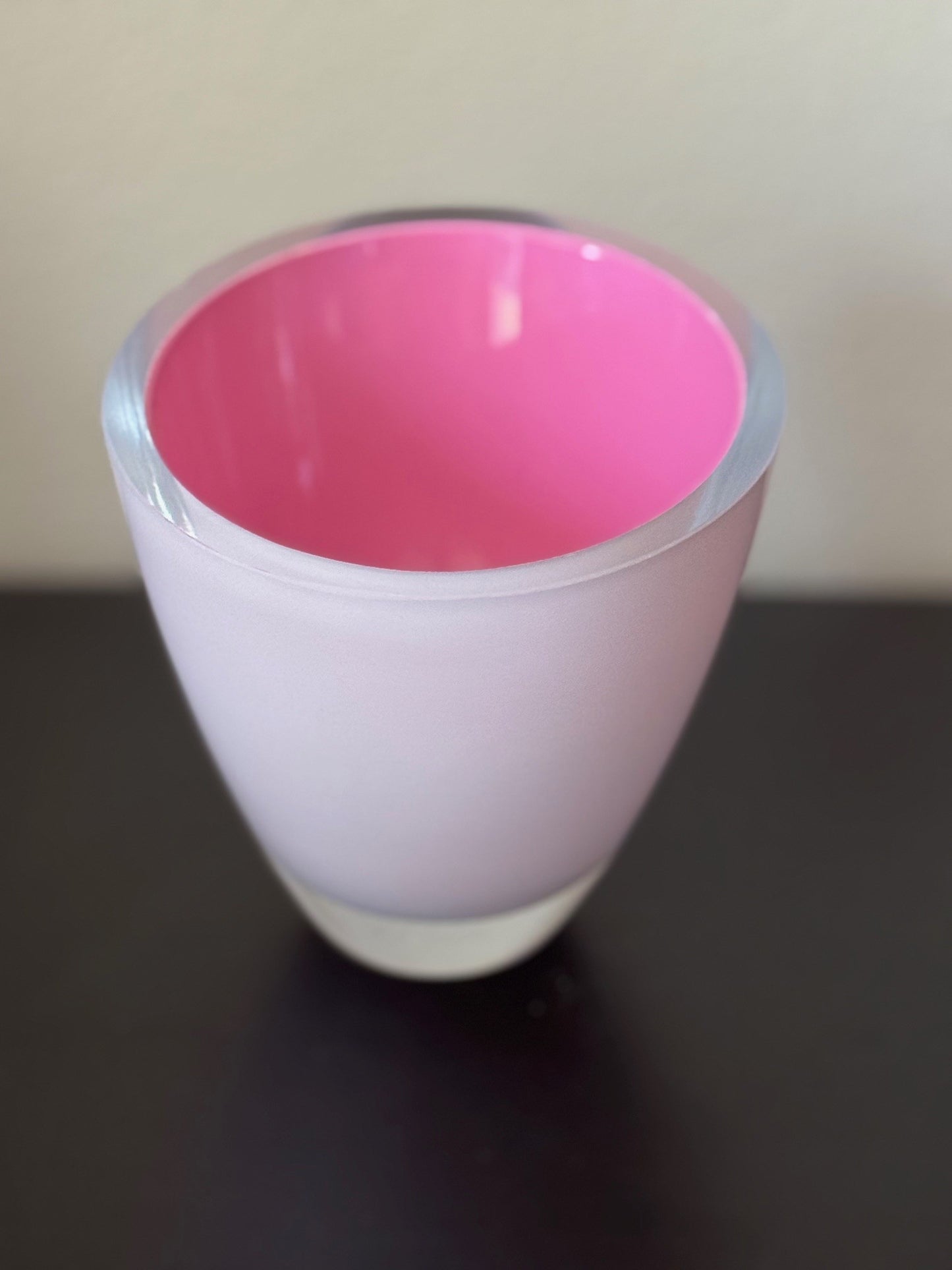 Pink and white cup on a dark surface with a light background