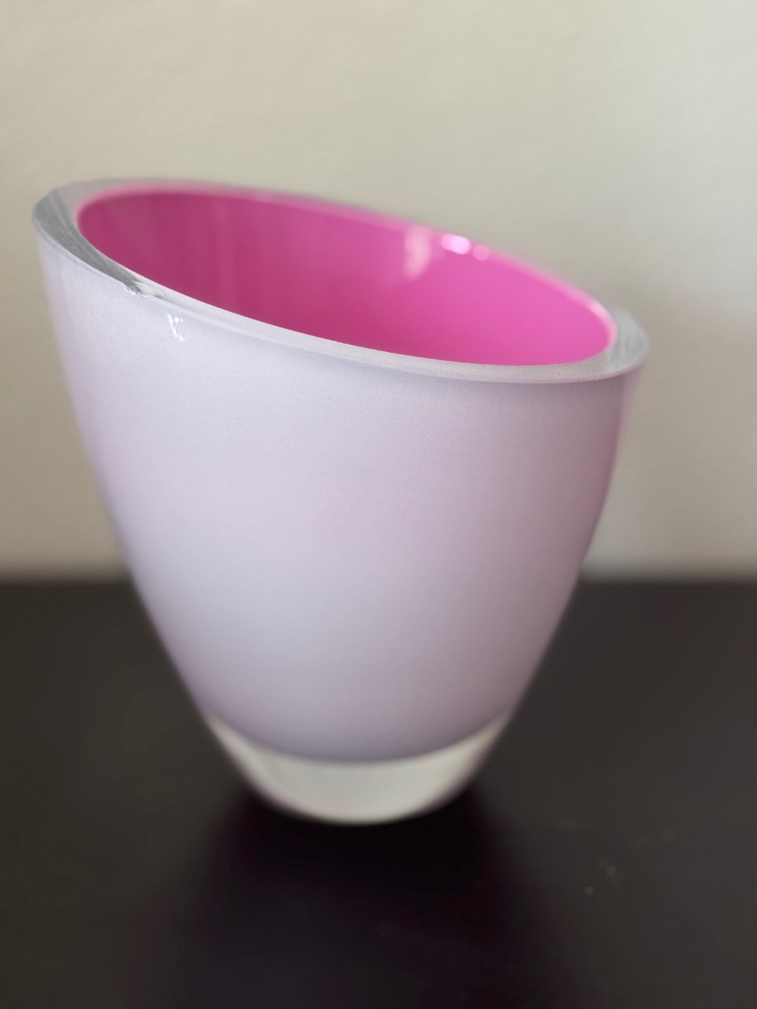 Pink and white cup on a dark surface with a neutral background