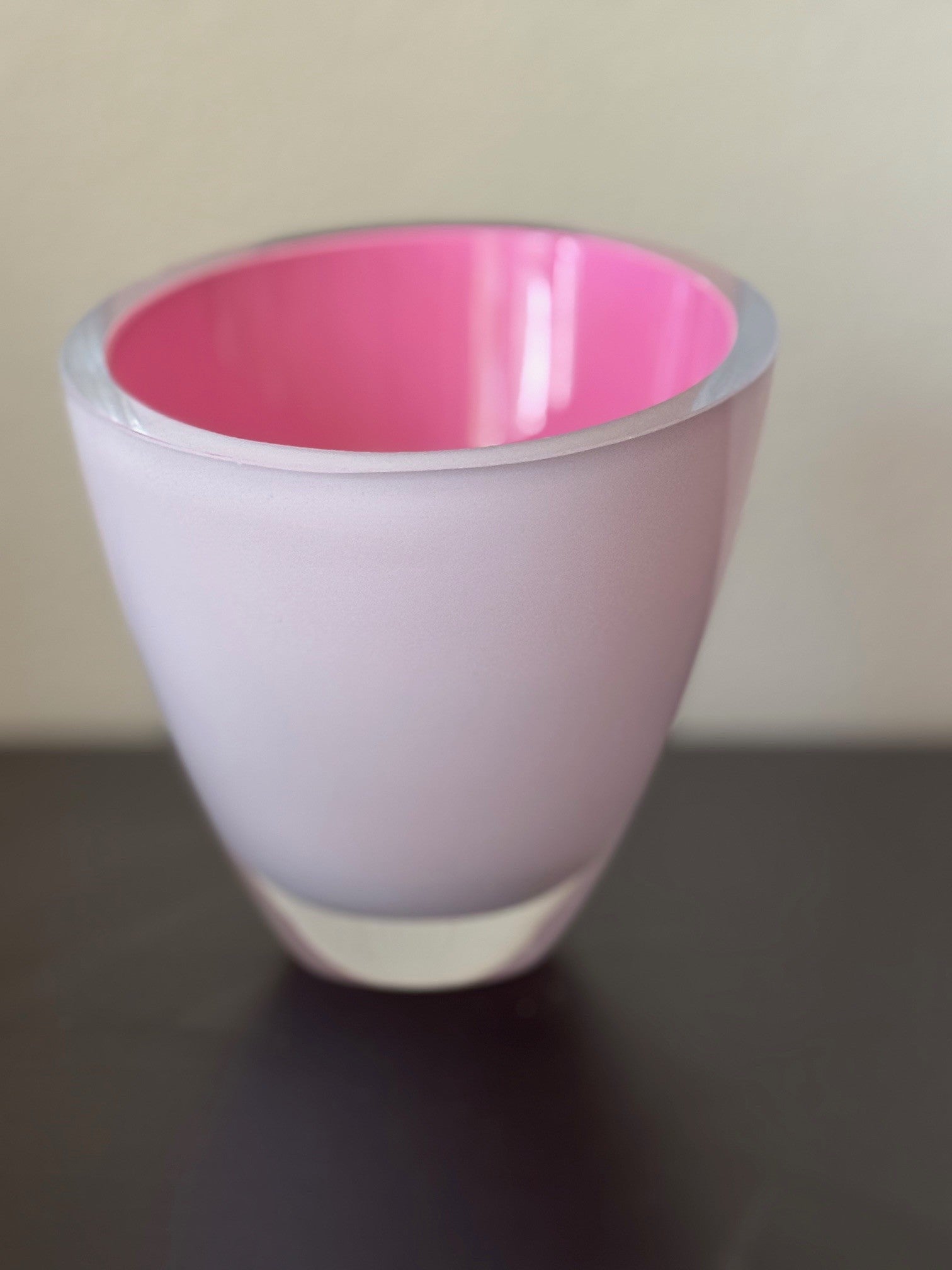 Pink cup with white rim on a dark surface
