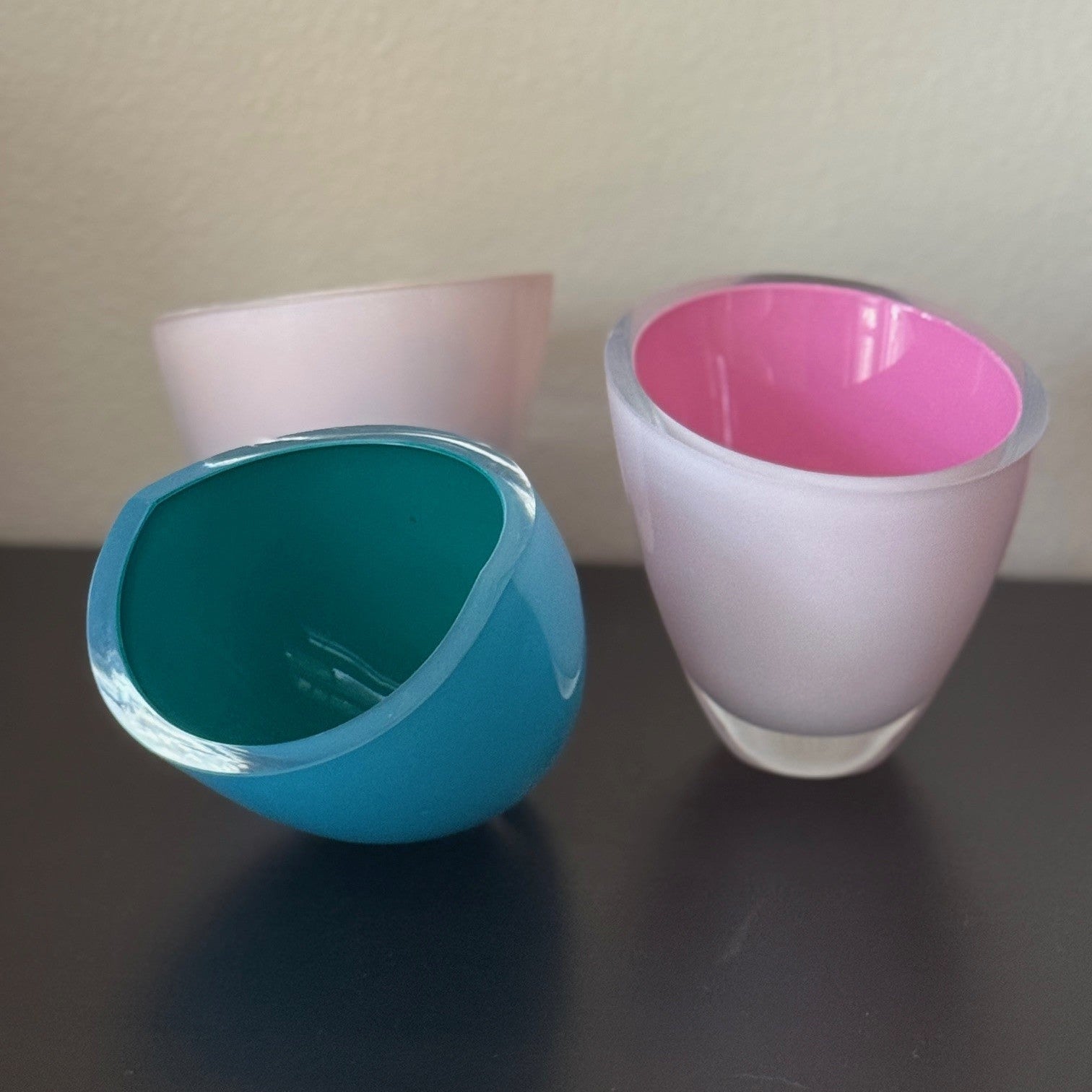Three colorful glass bowls on a dark surface with a light background