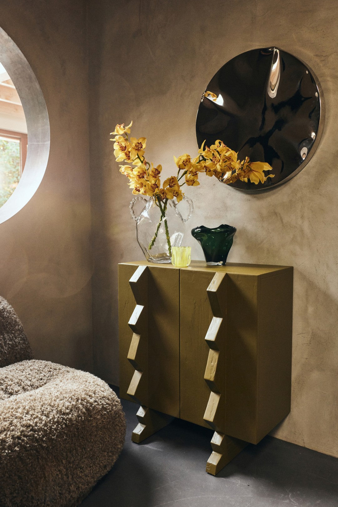Modern interior with a wooden sideboard, decorative mirror, and floral arrangement.
