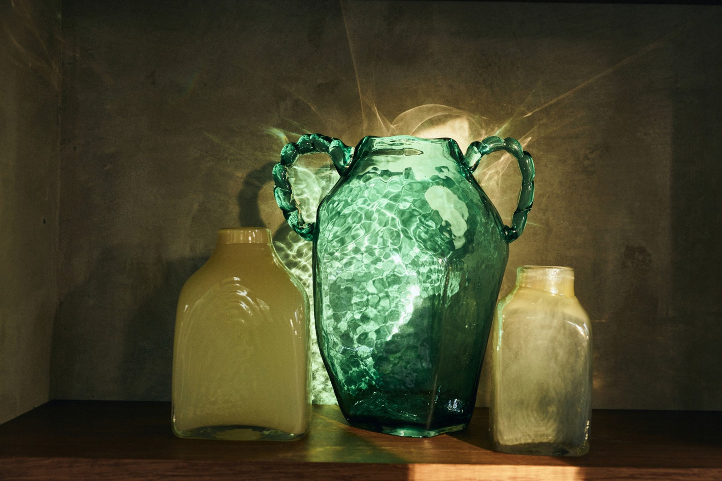 Three glass bottles with different designs on a wooden surface with a dark background