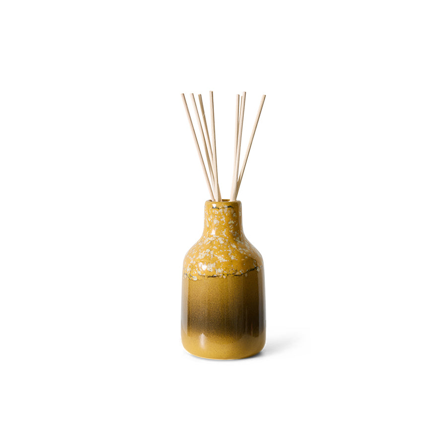 yellow stoneware vessel with reeds on a white background
