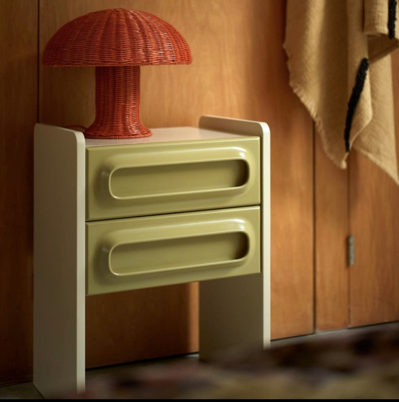 retro style nightstand with two drawers in sage green with cream with orange rattan mushroom table lamp