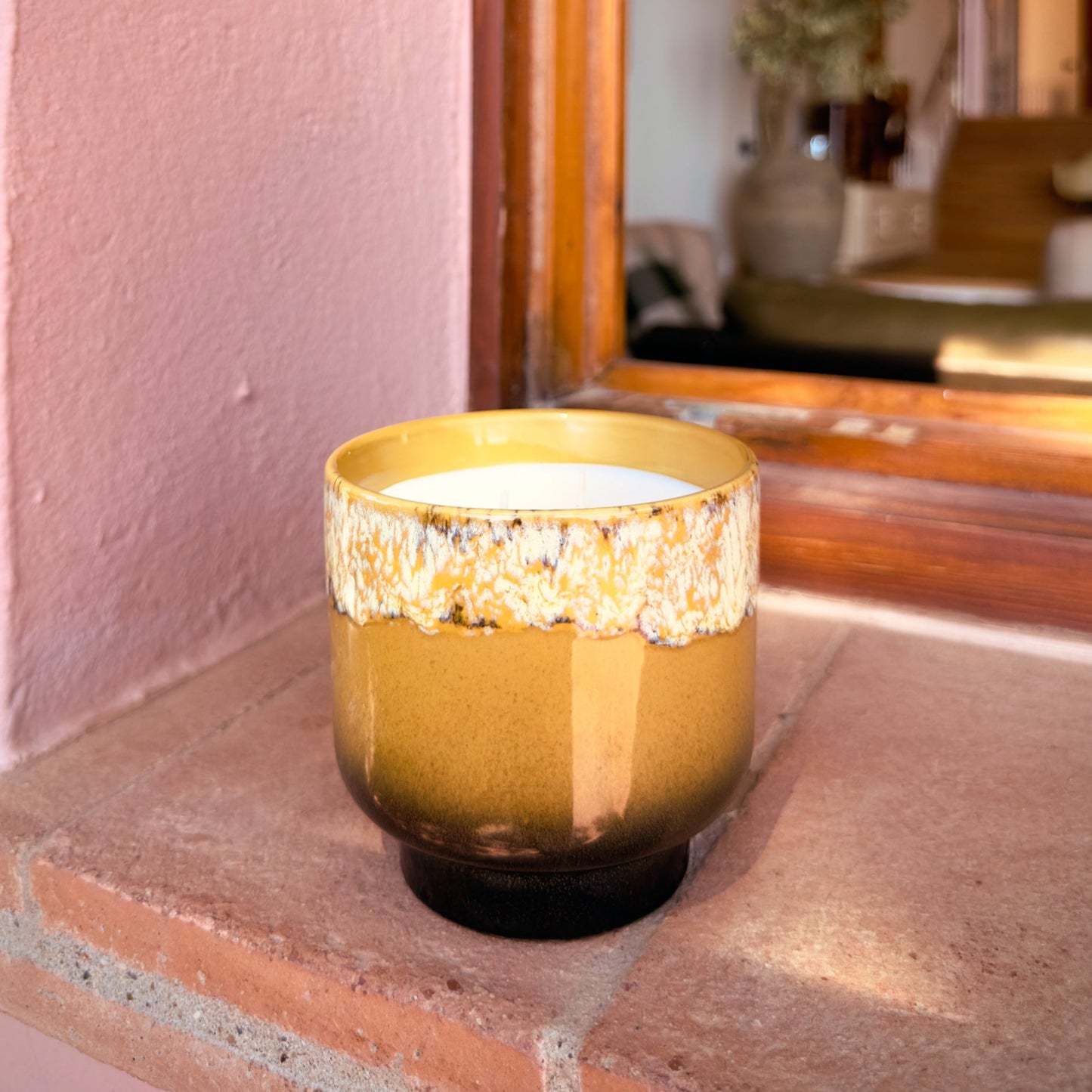 Gold candle holder on a windowsill with a blurred indoor background
