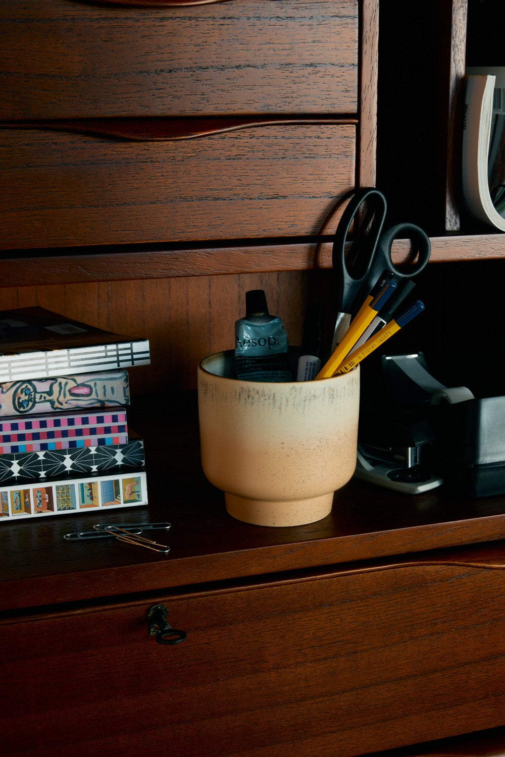 Ceramic cup with stationery items on a wooden desk