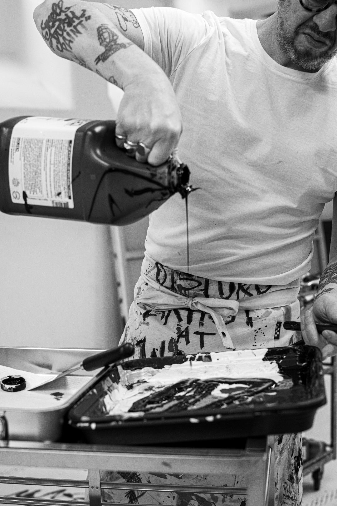 Person pouring paint from a bottle unto a tray in artist studio