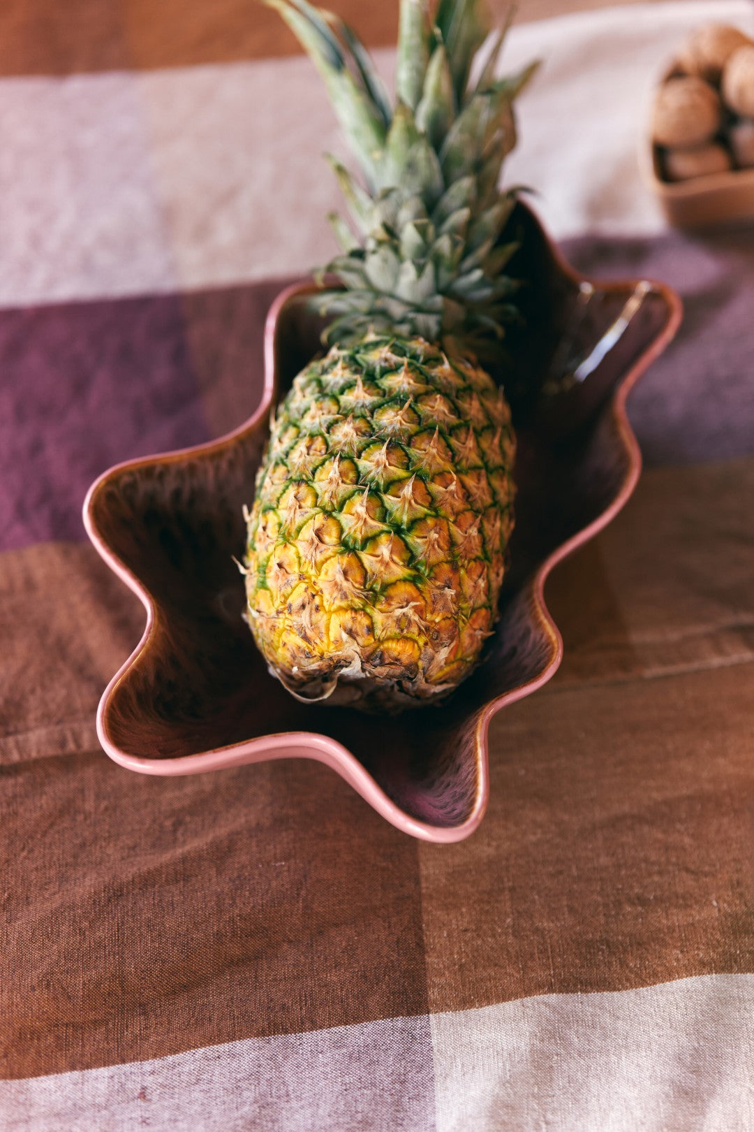 Pineapple on a decorative plate with a checkered tablecloth in the background