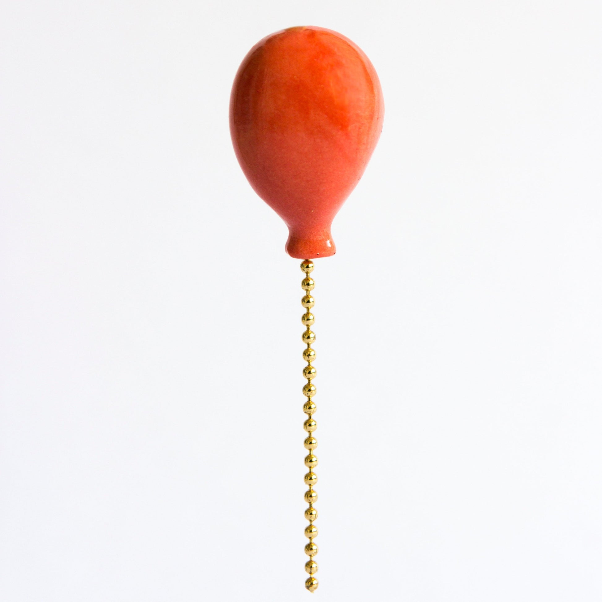 red balloon pin with gold colored chain 