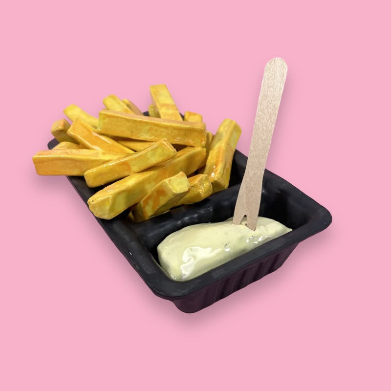 ceramic sculpture of black open container with fries and mayonnaise and small fork