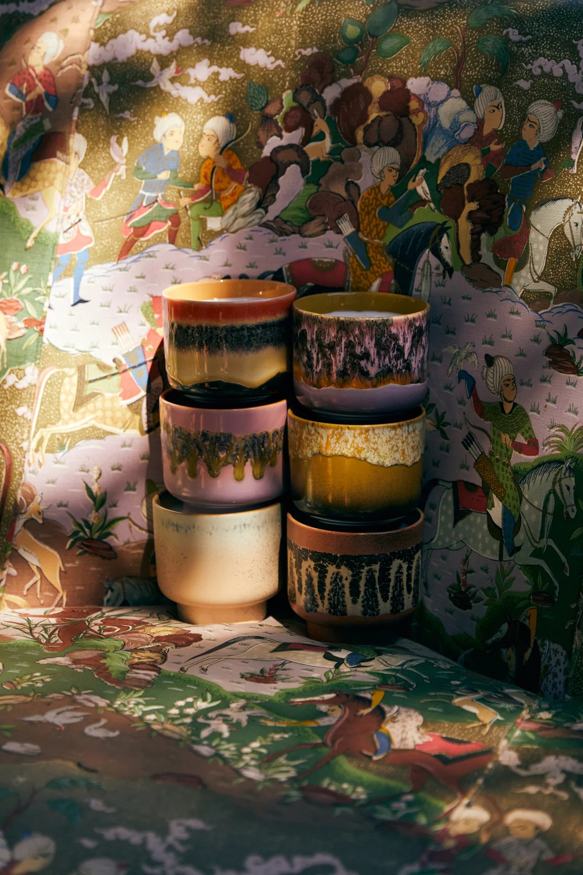 Stack of colorful ceramic pots on a table with a decorative background