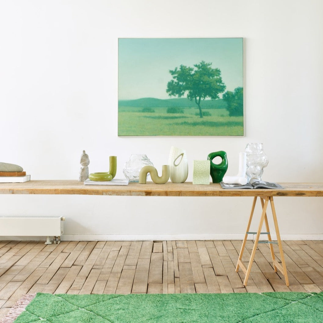 twisted green shiny object vase on teak wooden table with other green vases and objects