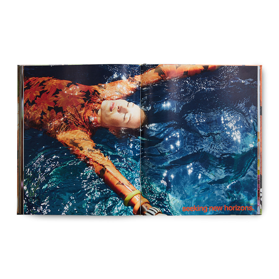 open book with 2 page photo of woman with orange dress in water