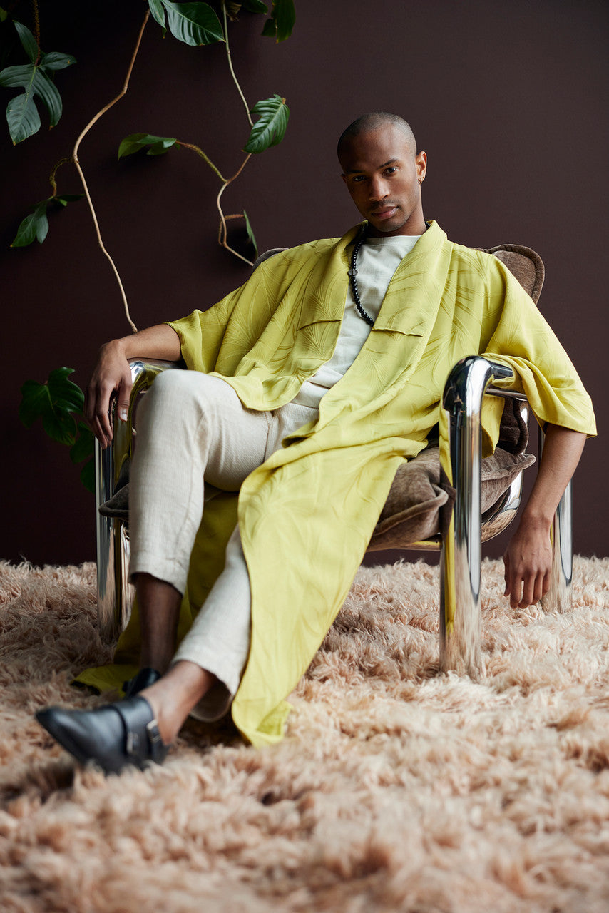 man with yellow robe sitting in a chrome retro lounge chair