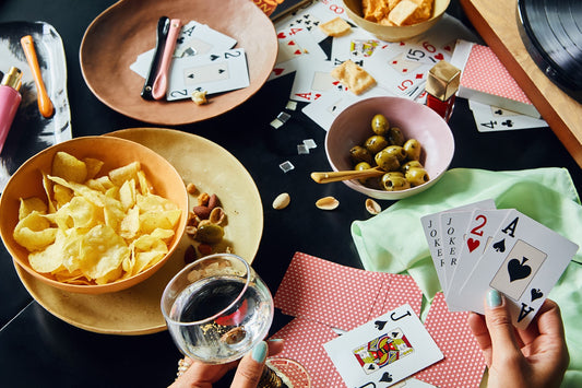table with snacks in porcelain bowls and plates and card game and make-up products