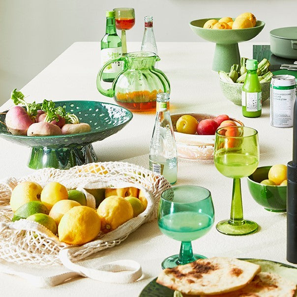 table with green serving bowl and lime and fern green colored wineglasses 