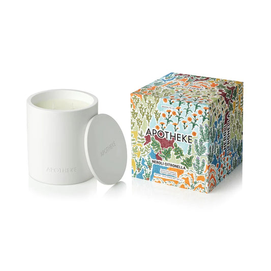 White candle with lid and colorful 'Apotheke' packaging on a white background