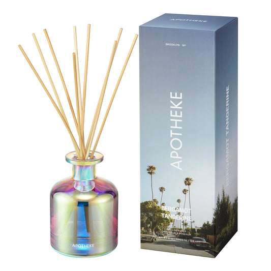 Apotheke diffuser with iridescent bottle and wooden sticks next to its packaging on a white background