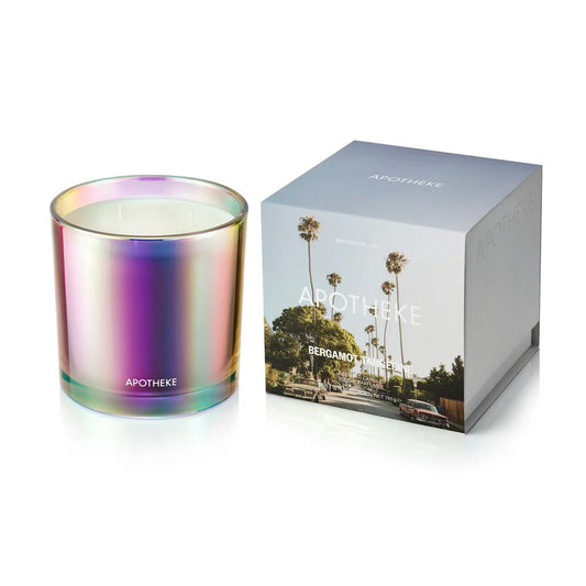 Iridescent candle with 'Apotheke' branding next to its packaging on a white background