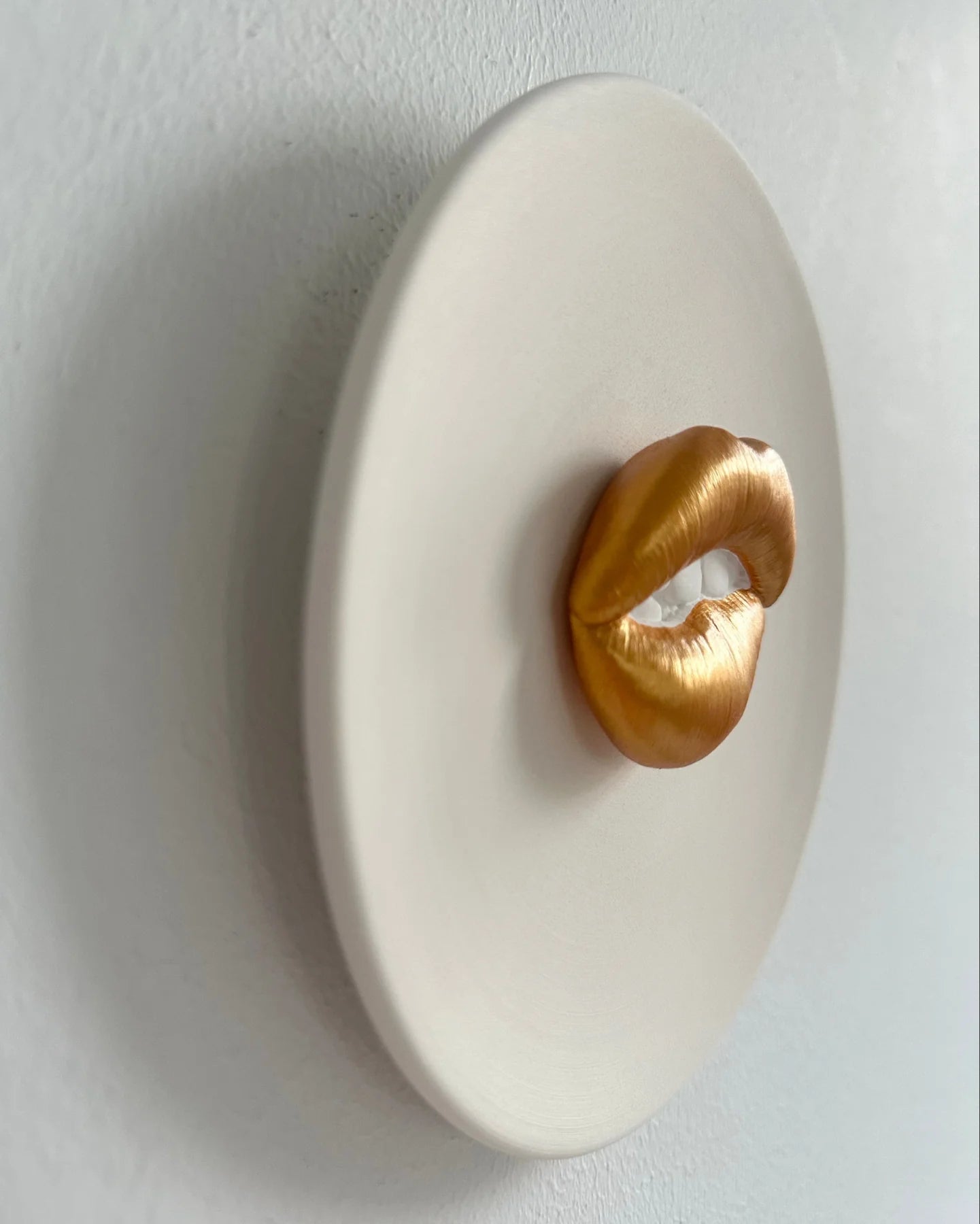 Decorative wall piece with gold lips on a white background