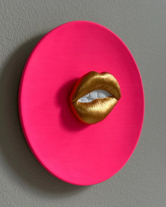 Pink circular object with gold lips on a gray background