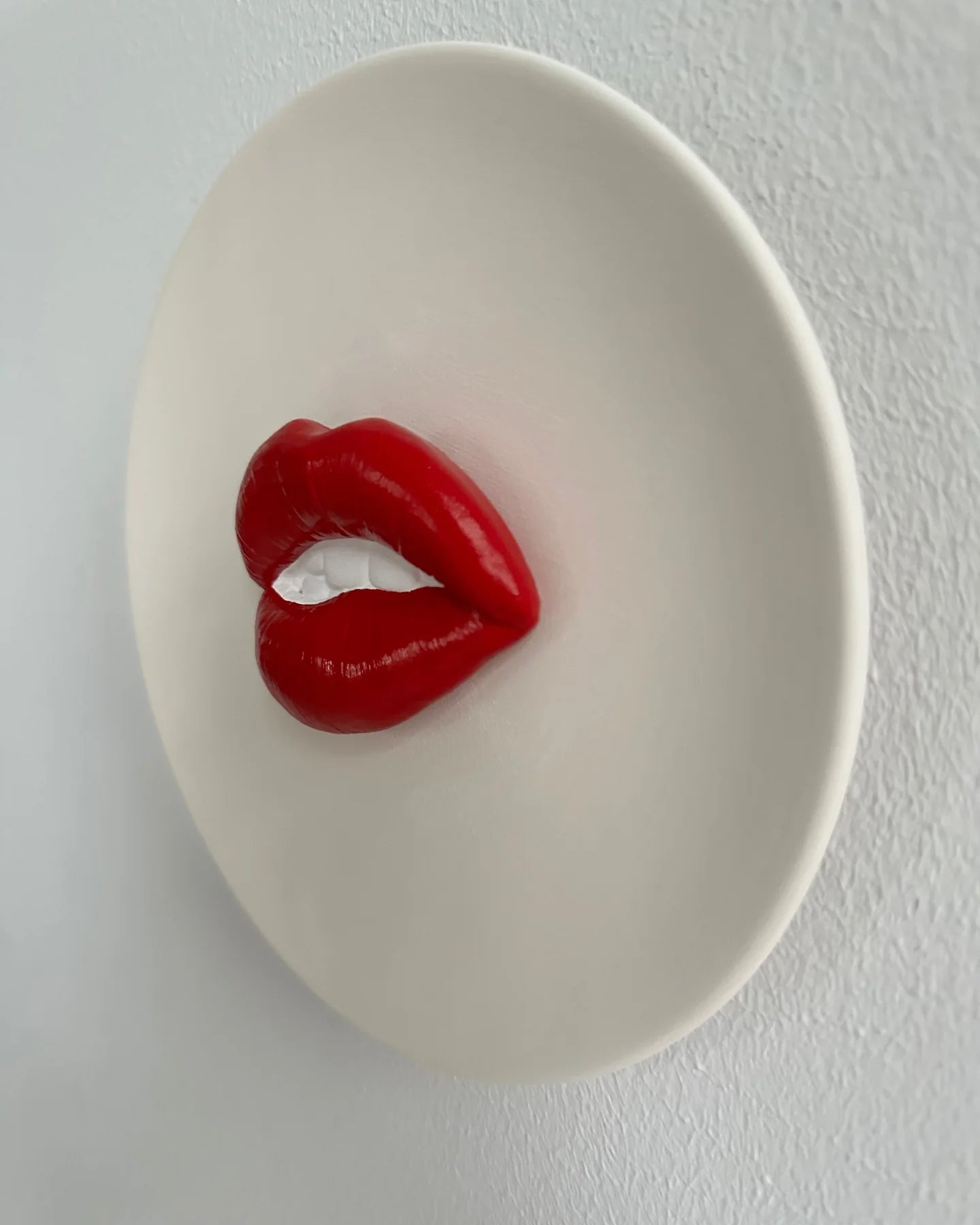 Red lips-shaped object on a white plate against a white background