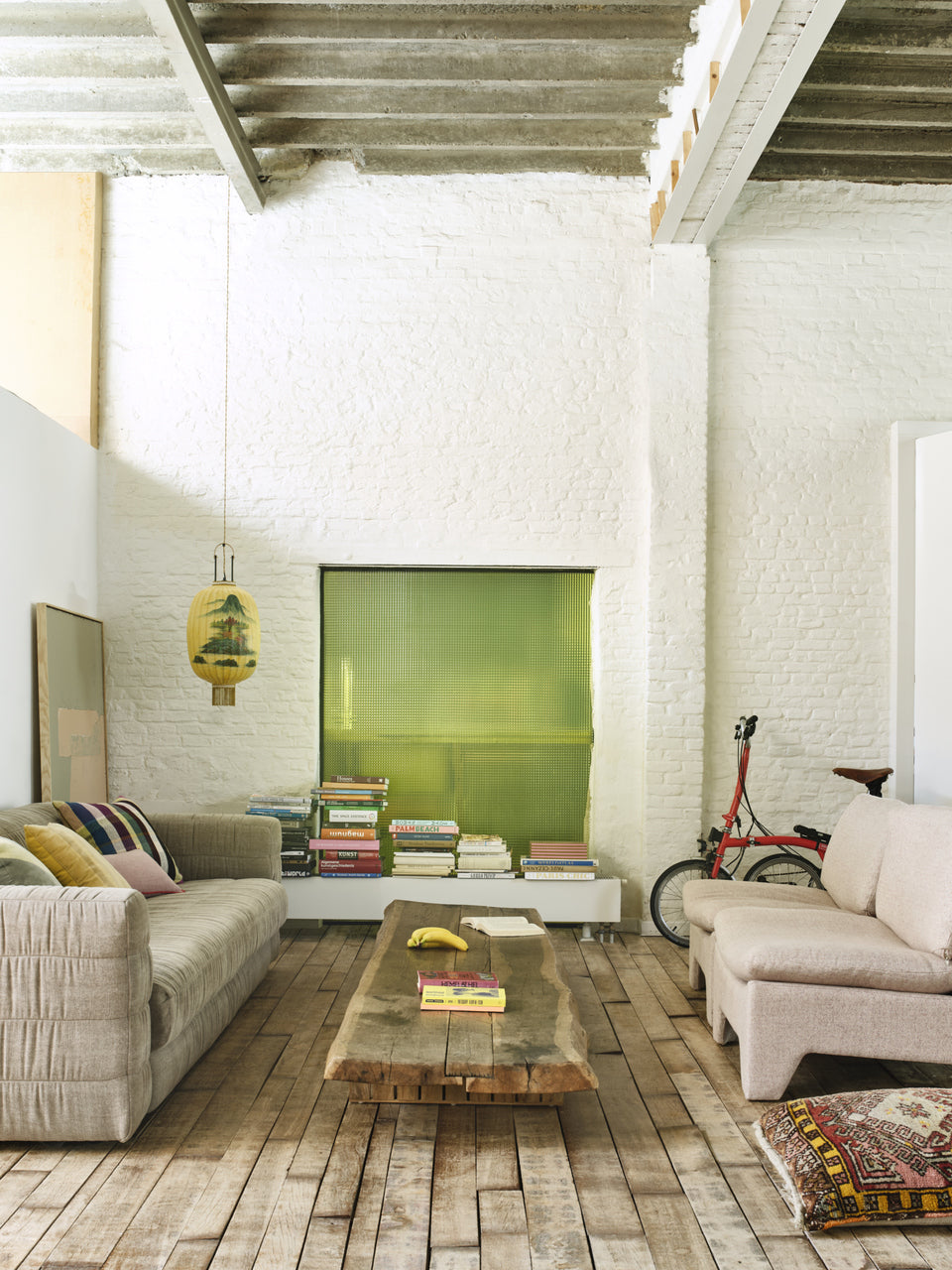 loft with wooden floor, white painted exposed brick wall and a large linen blend sofa in taupe color