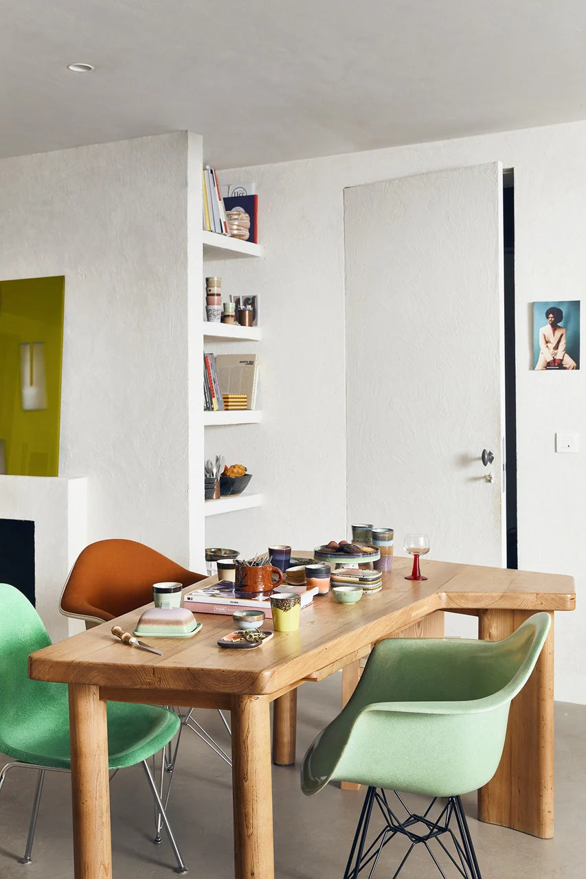 retro style table setting with colorful ceramics and green tub chairs