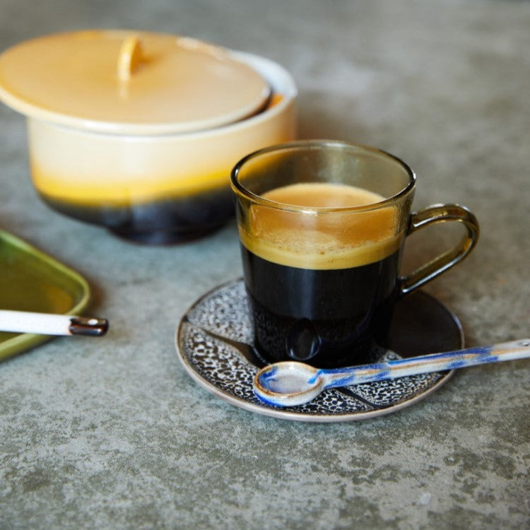 brown glass coffee cup on ceramic saucer with blue ceramic spoon